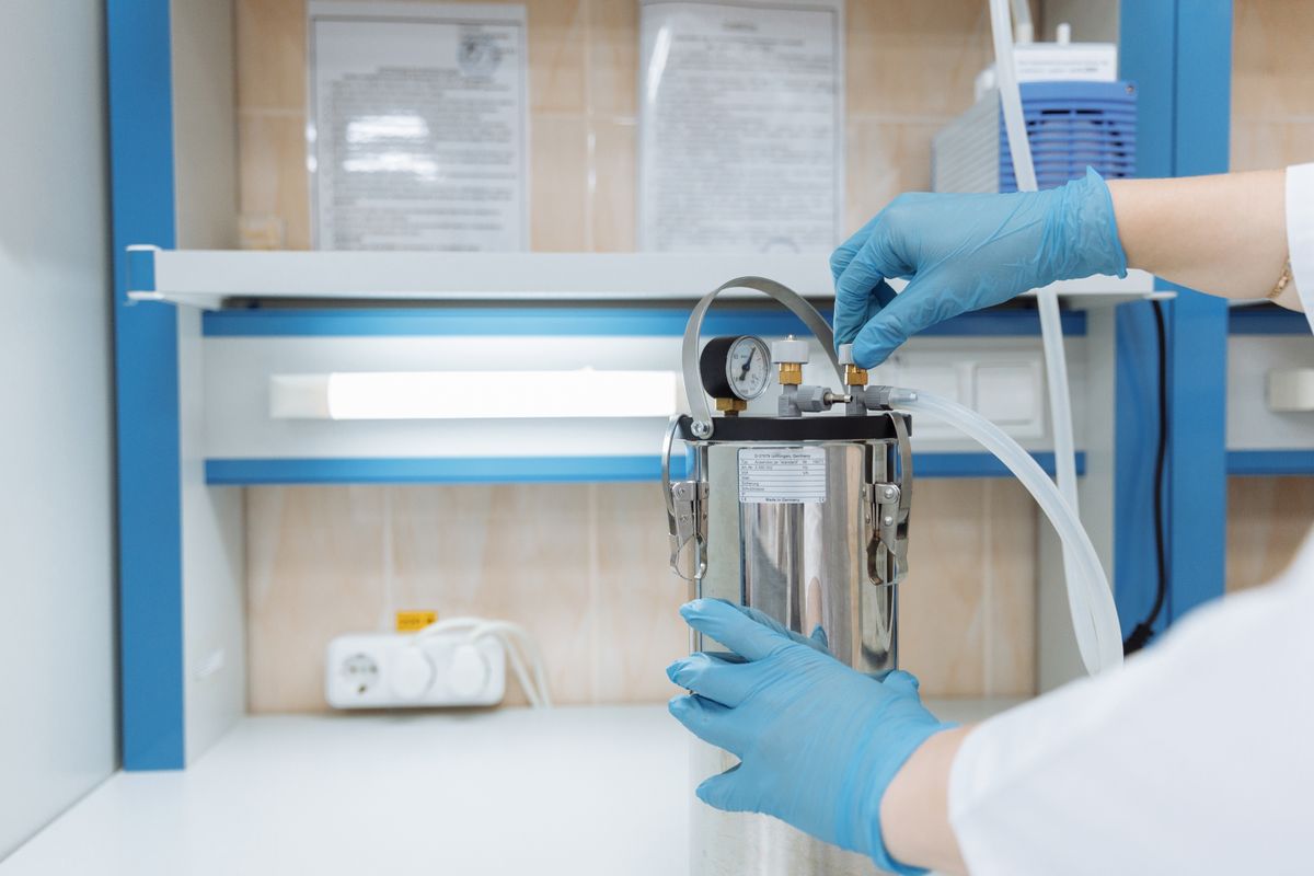 A researcher in gloves adjusting a laboratory instrument