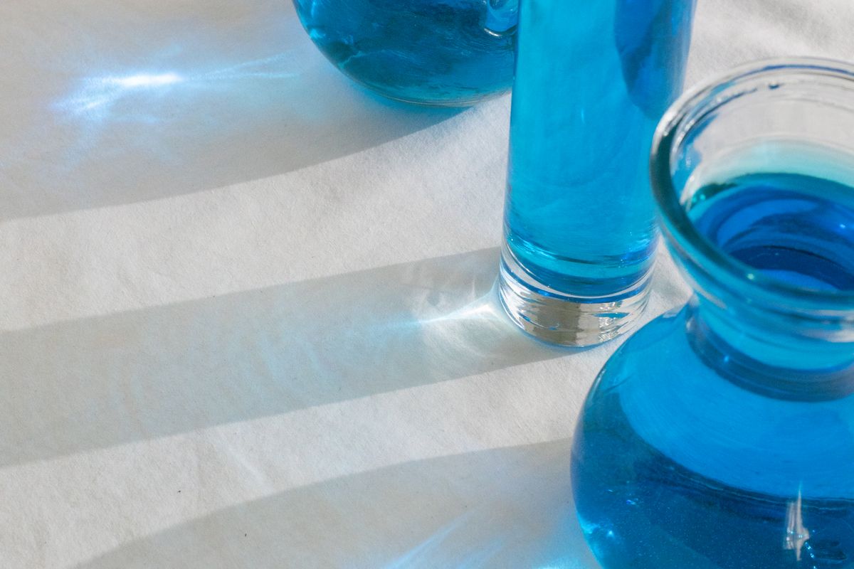 Glass vessels holding a blue solution in daylight