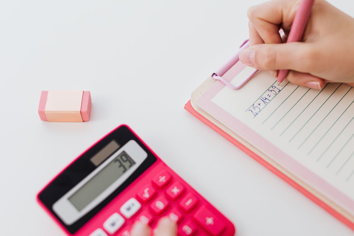 Hands using a calculator and writing equations in a notebook