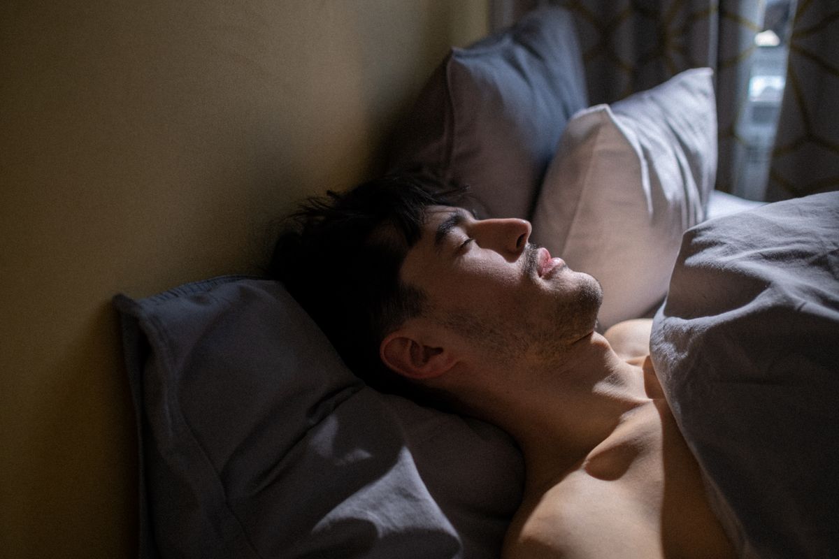 A man asleep in a dimly lit bedroom