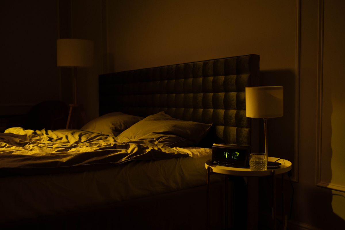 A dimly lit bedroom with an unmade bed