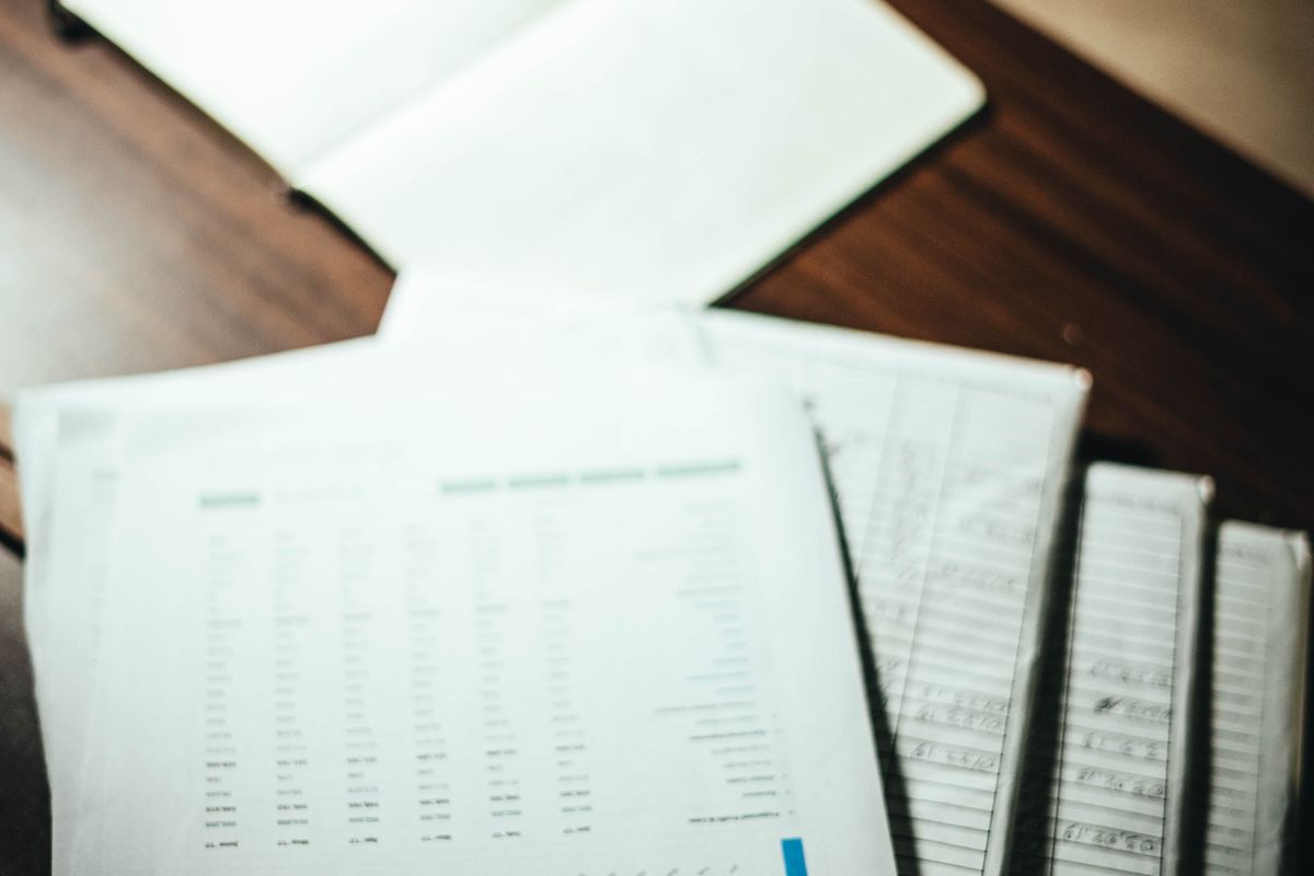 A stack of printed documents and data tables on a desk