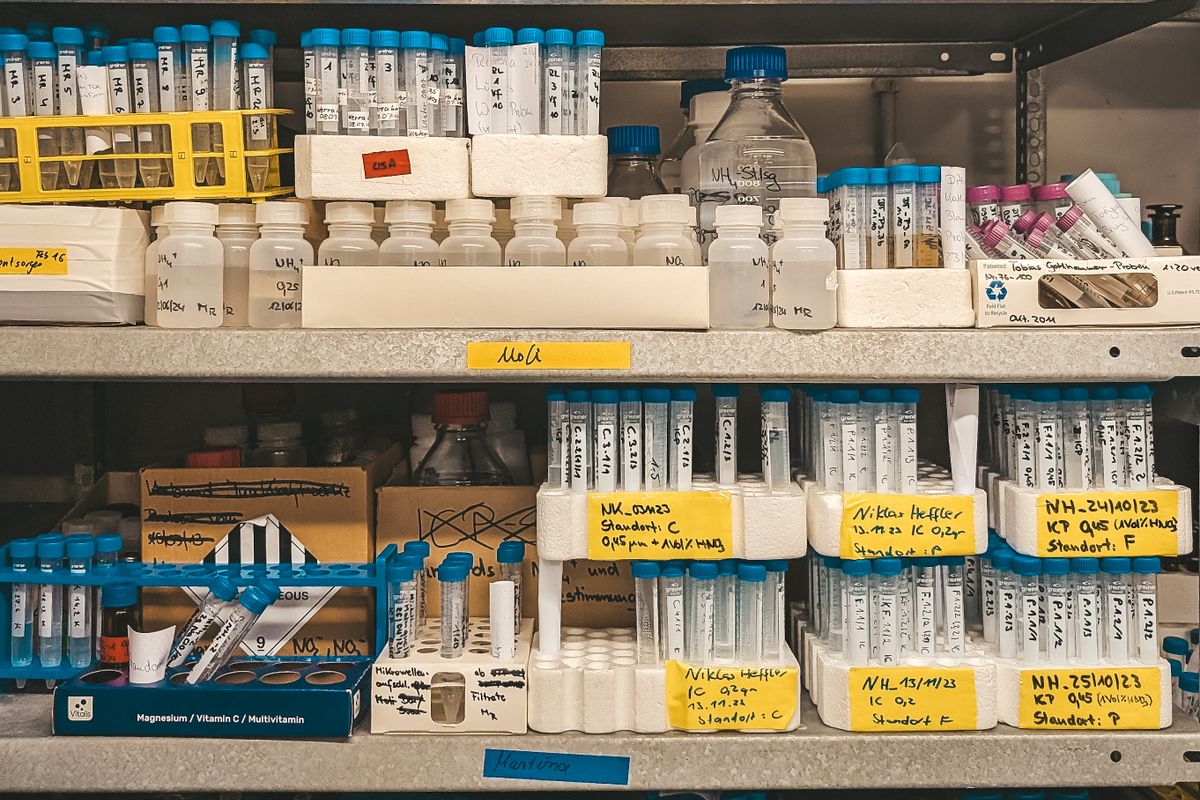 A laboratory shelf holding rows of labelled chemical vials