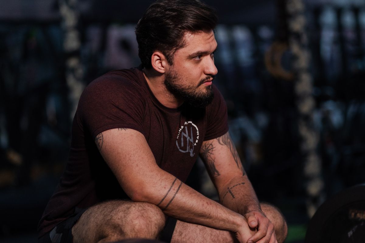 A man sitting and resting between sets in a gym